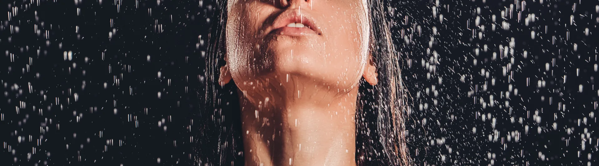Woman under a cold water shower, head tilted back